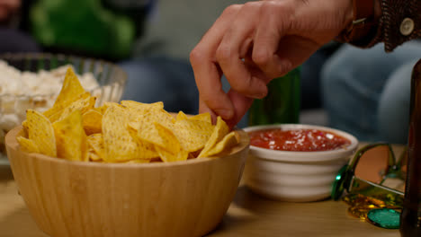 Close-Up-Of-Friends-At-Home-Or-In-Bar-Drinking-Alcohol-And-Eating-Tortilla-Chips-With-Salsa-Dip